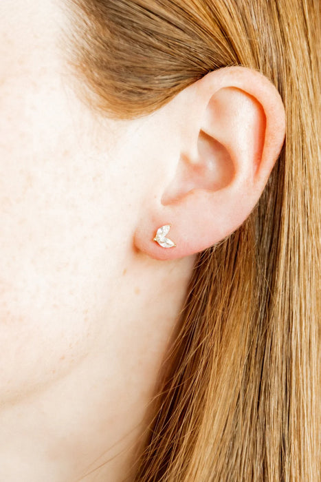 Close-up of an ear with a small earring worn by a person with blonde hair.