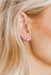 Close-up of a person wearing diamond stud earrings with blonde hair.