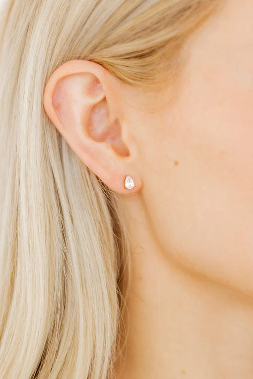 Close-up of an ear wearing a diamond earring with blonde hair.