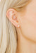 Close-up of an ear wearing a diamond earring with blonde hair.