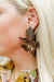 Close-up of a person wearing a large, decorative earring with a floral design.