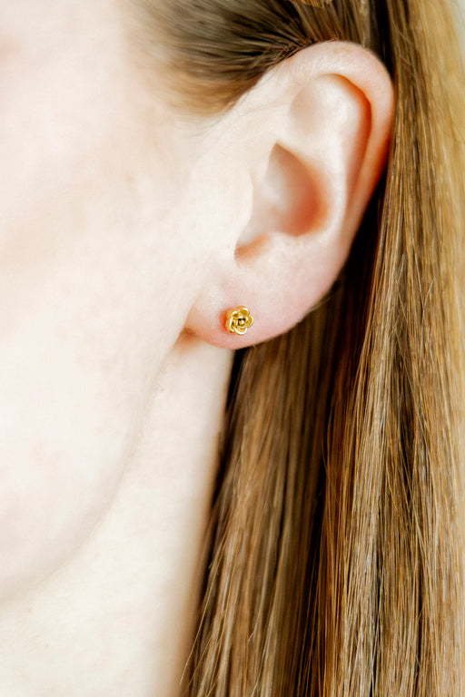 Close-up of an ear wearing a gold earring with a clear gemstone.