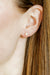 Close-up of an ear wearing a diamond stud earring with blurred background