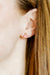 Close-up of an ear wearing a small earring with a blurred background