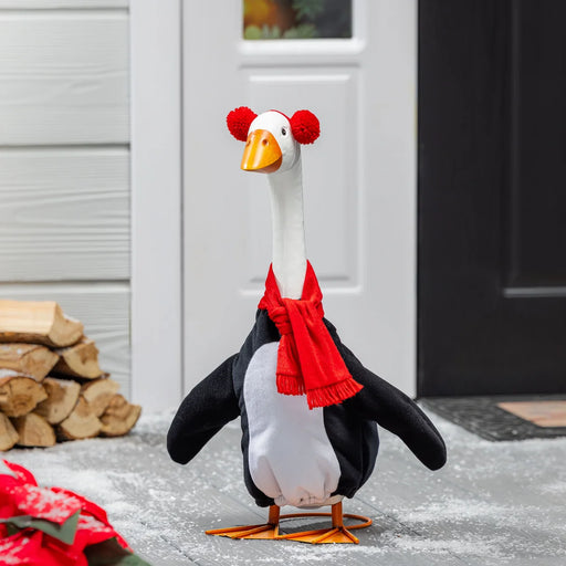 Decorative goose with a red scarf and pom-poms on a porch.