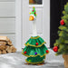 Decorative goose in a Christmas tree costume with a festive hat and ornaments, standing outdoors.