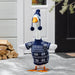Decorative goose wearing a sweater and hat in front of a house entrance.