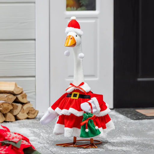 Decorative goose in a Santa outfit standing on a porch with logs stacked against a wall.