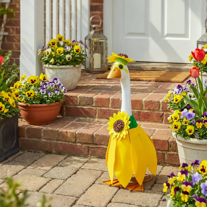 Decorative goose with a sunflower design on a porch with potted flowers.
