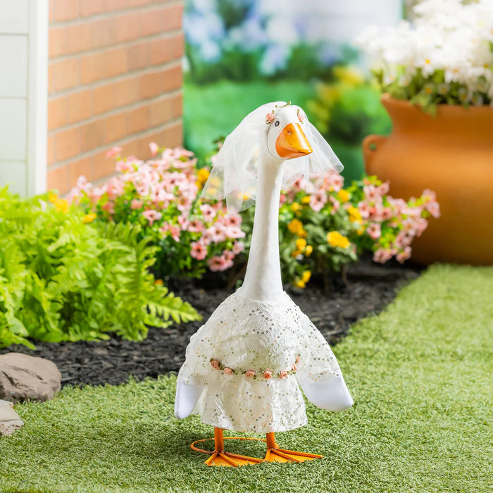 Decorative goose figurine with a white lace cover in a garden setting