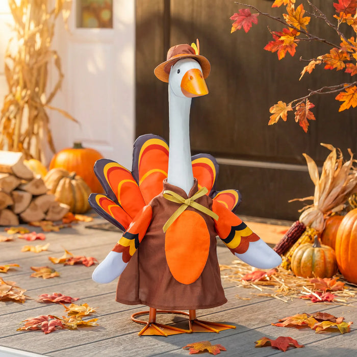 Decorative goose in a turkey costume with autumn decorations on a wooden floor.