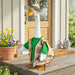 Decorative goose statue wearing a hat and vest on a wooden porch.