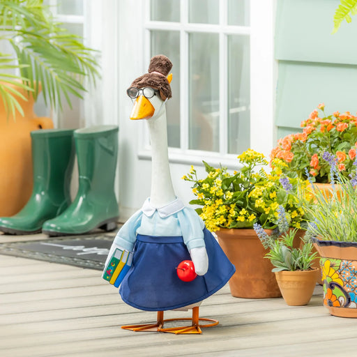 Decorative goose figurine with a hat and skirt in a garden setting