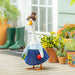 Decorative goose figurine with a hat and skirt in a garden setting