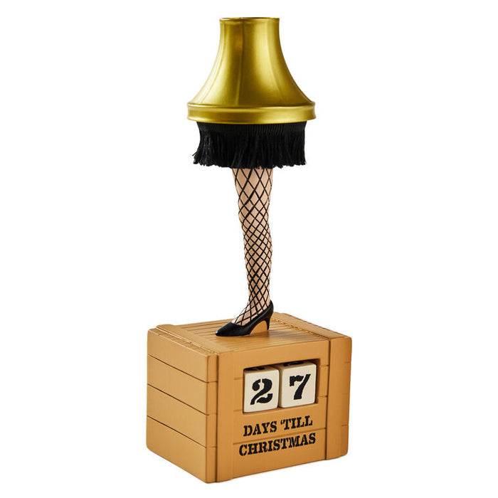 Decorative lamp with a gold shade, black fringes, fishnet stockings, and high heels on a white background.