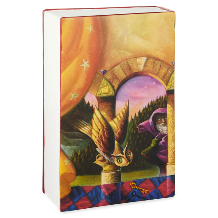 A hardcover book with a colorful fantasy illustration on the cover, featuring an owl, a hooded figure, stars, and an archway. The book is photographed on a clean white background.