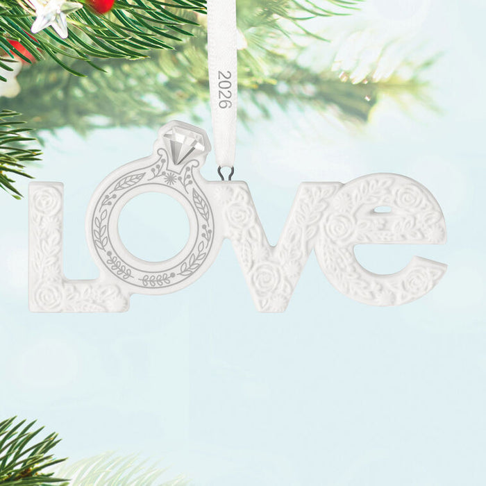 Decorative ornament with 'love' and a ring design, hanging on a tree branch.