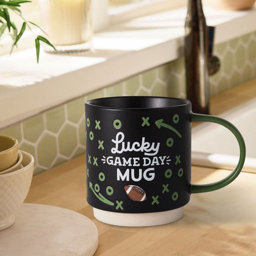 Black mug with 'Lucky Game Day Mug' text on a kitchen counter.