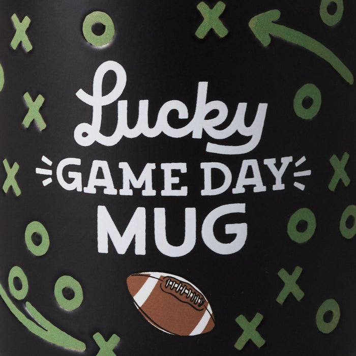 Black mug with 'Lucky Game Day Mug' text and football design on a black background with green symbols.