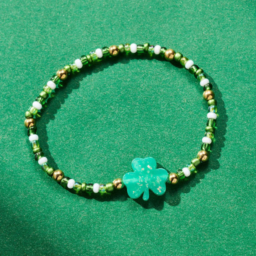 Green beaded bracelet with a clover charm on a green background