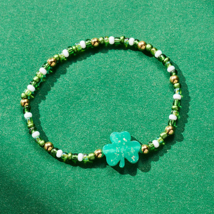 Green beaded bracelet with a clover charm on a green background