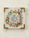 Decorative sign with floral design and motivational quote on a light background