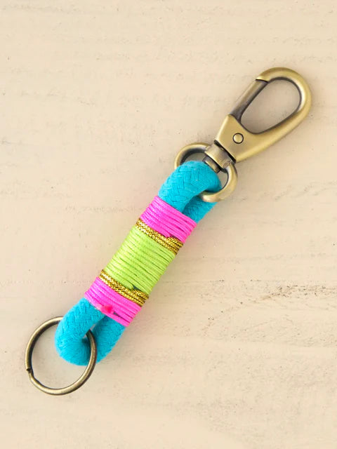 Keychain with colorful strap and gold carabiner on beige background
