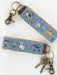 Keychain with embroidered cat designs on a blue fabric strap.
