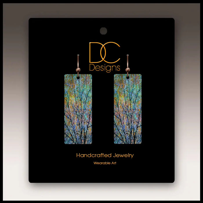 Pair of earrings on a black card with 'DC Designs' branding
