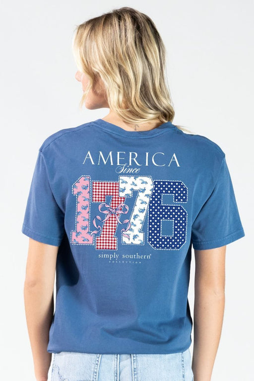 Woman wearing a blue t-shirt with 'America Since 1776' design on the back.