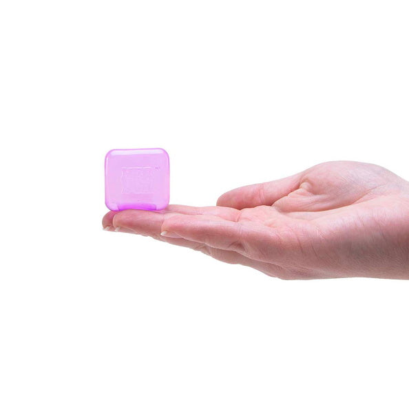 Hand holding a small purple cube against a white background