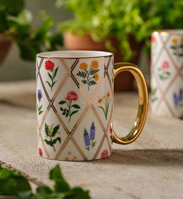 Decorative mug with floral patterns on a surface with plants in the background