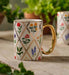 Decorative mug with floral patterns on a surface with plants in the background