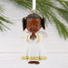 Angel figurine ornament with braided hair and a white outfit with gold patterns, hanging from a branch.