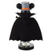 A decorative tabletop figure styled like a character wearing a black bat-wing cape, a gray top hat with black ears, and an orange band, standing on a round black base against a plain white background.