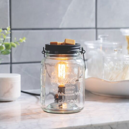 Glass jar with a lit candle inside on a kitchen counter