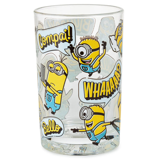 A clear glass tumbler featuring cartoon Minions characters and speech bubbles, including the names Compai, Whaaaam, and Bello, on a white background.