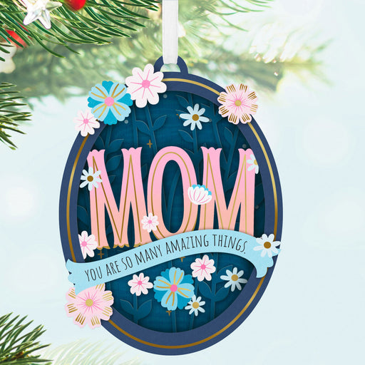 Decorative ornament with 'MOM' text and floral design on a Christmas tree.