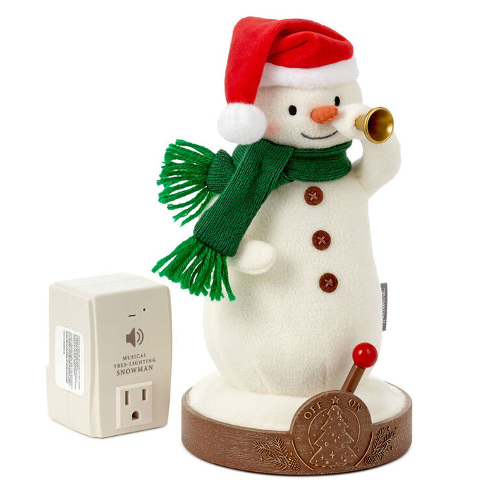 Snowman figurine with a red hat, green scarf, and bell, next to a white electrical device on a white background.