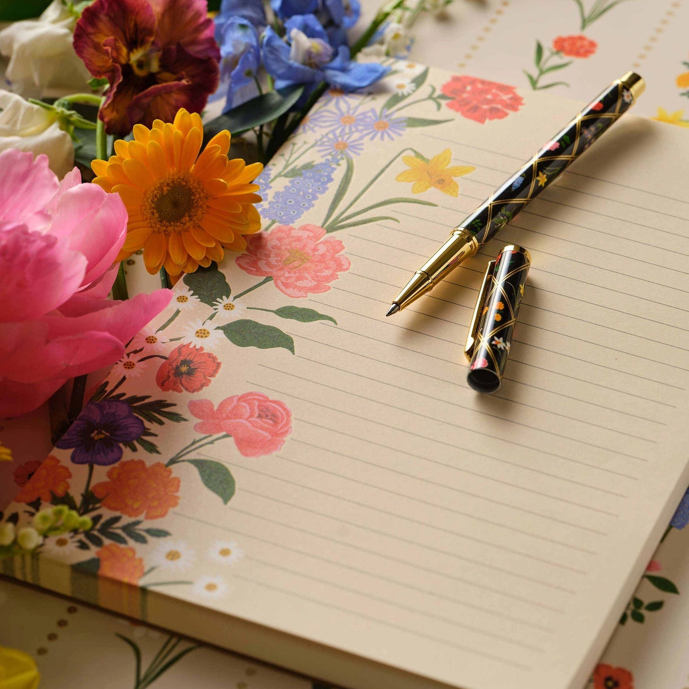Floral notebook with a decorative pen on a floral background