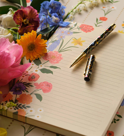 Floral notebook with a decorative pen on a floral background