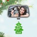 Car mirror with a reflection of a woman holding keys, Christmas tree ornament labeled 'New Driver 2026' on a light blue background.