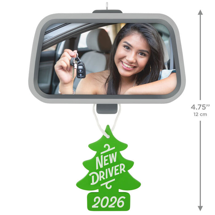 Car mirror with a woman holding keys, 'New Driver 2026' air freshener, and dimensions indicated.