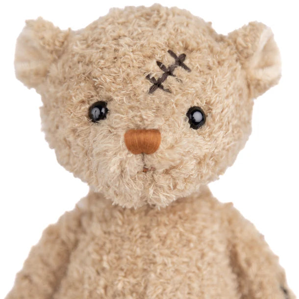 Teddy bear with a bandage on its head against a white background
