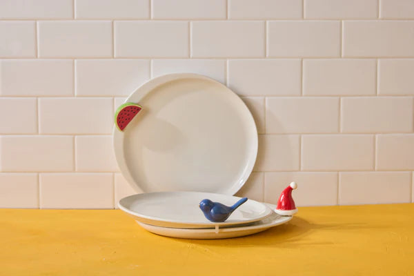 Set of ceramic plates with decorative birds on a yellow table against a beige tiled wall.