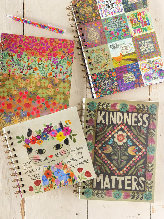 Colorful notebooks with floral designs and motivational text on a wooden surface.