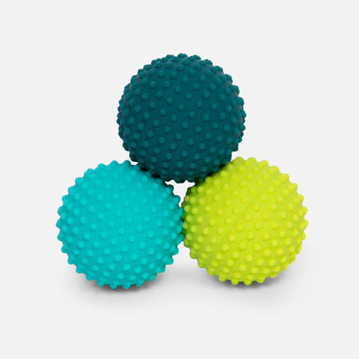 Three textured massage balls in teal, blue, and green on a light gray background