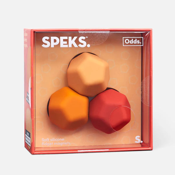 Speks product packaging with three geometric silicone balls in orange, red, and gold on a beige background.