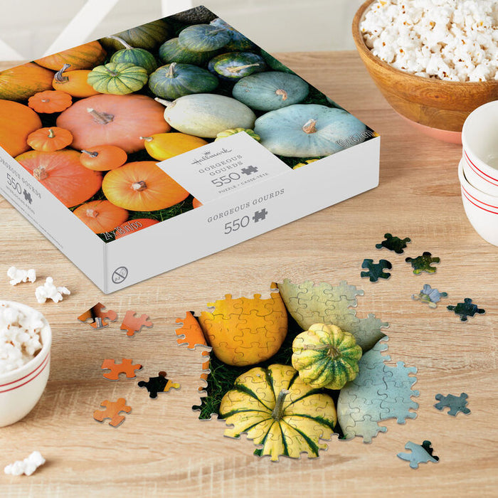 Puzzle with gourd-themed packaging on a table with puzzle pieces and popcorn.