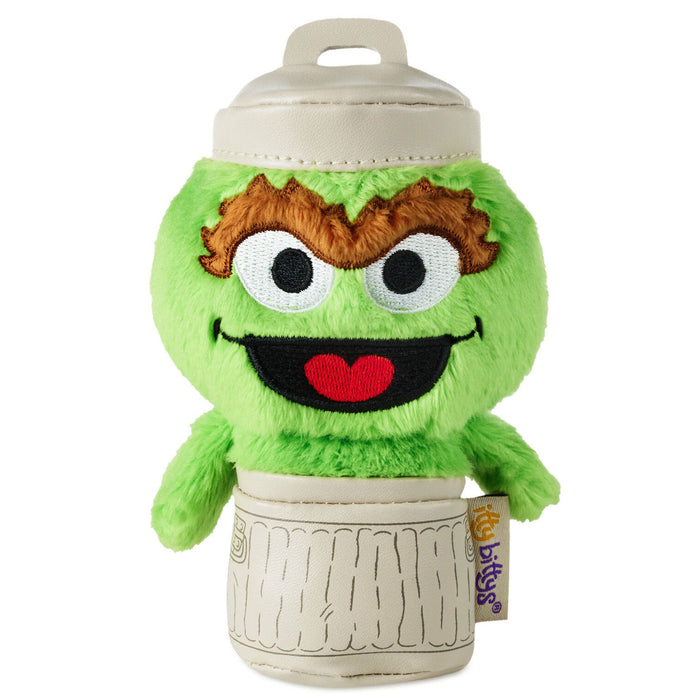 Green plush toy with a smiling face on top of a beige container, featuring the 'Frisbee' brand.